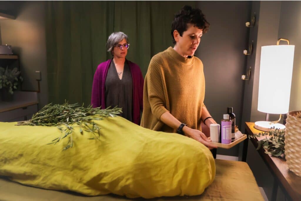 two women by a mock dead body for a small funeral service