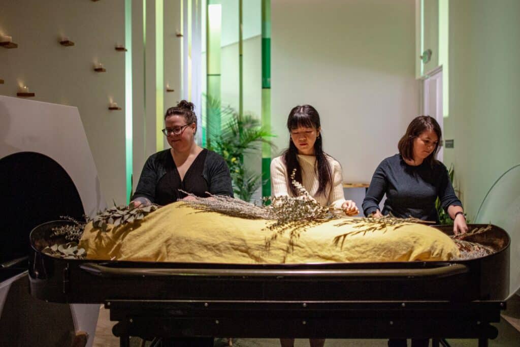 three women by a body during a funeral service