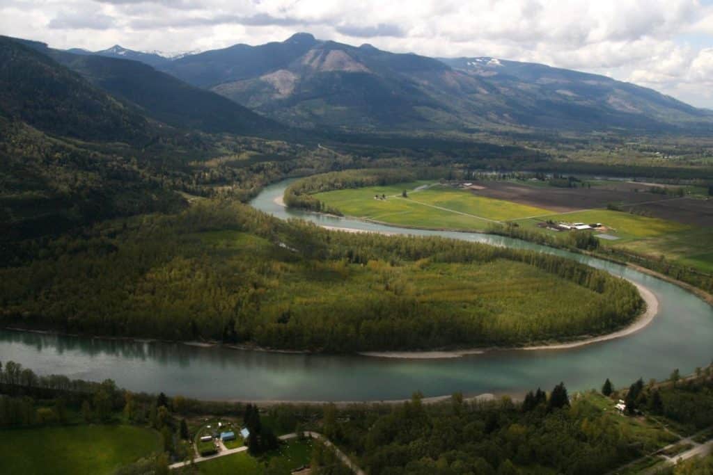 mountains with clouds behind it and a winding river in front