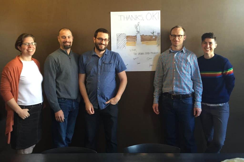 five people standing by a poster of a composting system