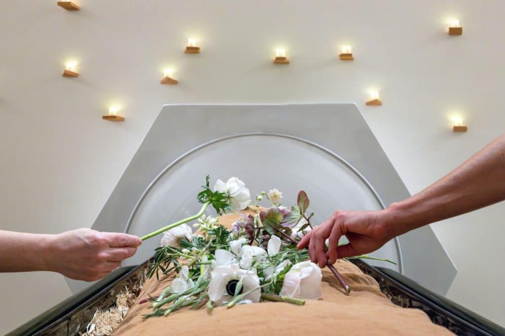 hands holding flowers over a shrouded mannequin