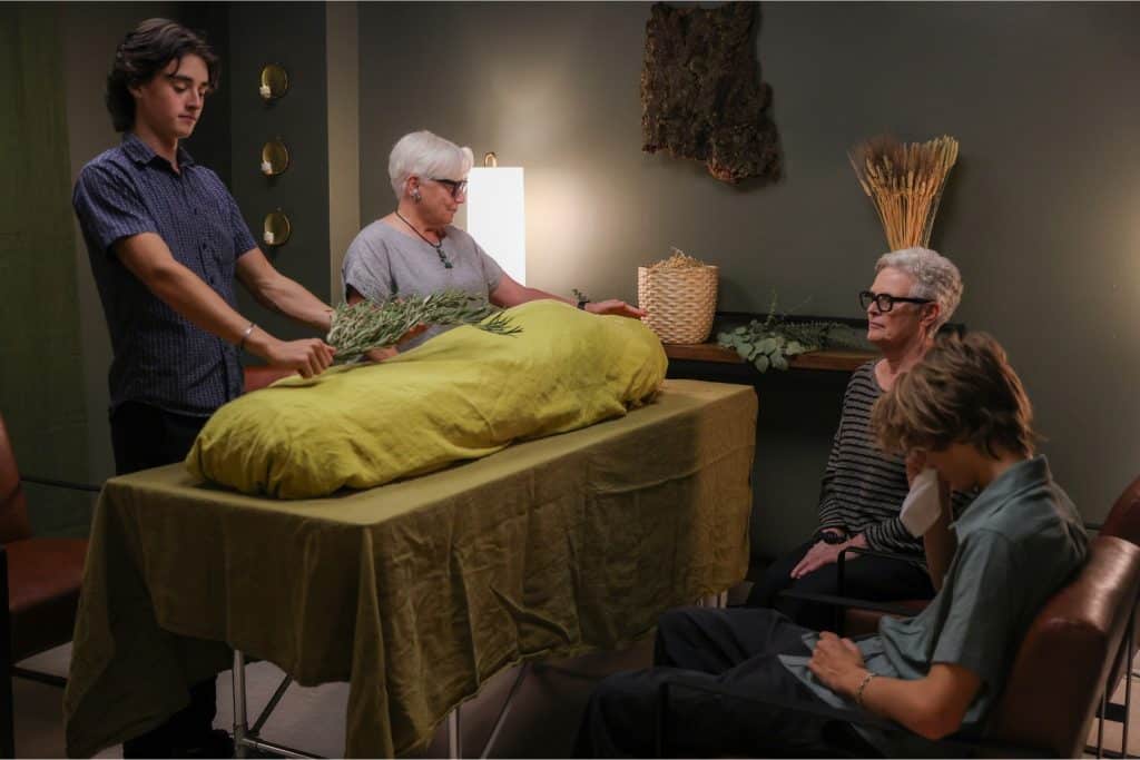 Guests around a shrouded mannequin at a funeral home
